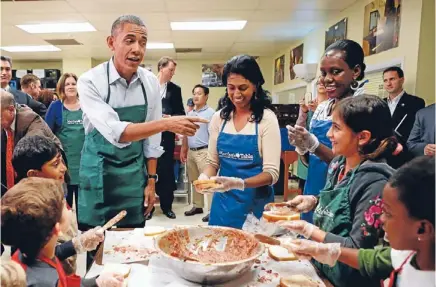  ?? Photo: REUTERS ?? Time out: As the waiting goes on over a debt ceiling agreement, President Barack Obama greets children and volunteers during a visit to Martha’s Table, a kitchen that prepares meals for the needy, in Washington.