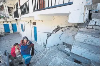  ?? RAJESH KUMAR SINGH PHOTOS THE ASSOCIATED PRESS ?? Residents leave their home in Joshimath, in India’s Himalayan mountain state of Uttarakhan­d in January after large cracks emerged in hundreds of homes making them unlivable. Below, a demolished hotel in the same town. Experts and activists say constructi­on aimed at encouragin­g tourism and hydropower projects in the region is contributi­ng to the sinking of land.