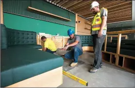  ?? NWA Democrat-Gazette/CHARLIE KAIJO ?? Nathan Richardson (center) of M&S Cabinets and Jon Beer (right) of Maderas Collective install seating Saturday at a work/play space called The Holler at 8th Street Market in Bentonvill­e. The South Market will soon be opening and host a variety of...