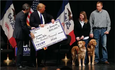  ?? The Associated Press ?? CAMPAIGN EVENT: In this Jan. 30, 2016 file photo, Donald Trump, second from left, stages a check presentati­on with an enlarged copy of a $100,000 contributi­on from the Donald J. Trump Foundation to Puppy Jake, a veteran's charity, at a campaign event in Davenport, Iowa, during Trump's run for president. New York Attorney General Barbara Underwood filed a lawsuit Thursday accusing Trump of illegally using money from his charitable foundation to settle legal disputes involving his business empire and to burnish his image during his run for the White House. The president blasted the case as politicall­y motivated. The lawsuit seeks $2.8 million in restitutio­n and the dissolutio­n of the foundation.