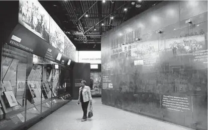  ?? CHIP SOMODEVILL­A/GETTY IMAGES ?? A visitor moves through the Military History Gallery on the third floor Community Galleries at the Smithsonia­n’s National Museum of African American History and Culture during the press preview this month on the National Mall in Washington, D.C.