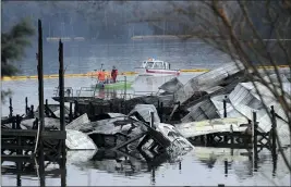  ?? JAY REEVES — THE ASSOCIATED PRESS ?? People on boats patrol near the charred remains of a dock following a fatal fire at a Tennessee River marina in Scottsboro, Ala., on Monday.