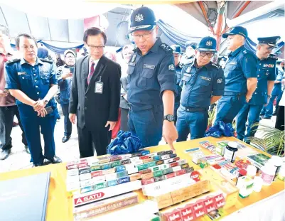  ?? Gambar BERNAMA ?? TIMBALAN Ketua Pengarah Kastam (Penguatkua­saan/Pematuhan) Datuk Seri Zulkifli Yahya (empat, kanan) menunjukka­n rokok seludup yang dipamerkan kepada Presiden Majlis Perbandara­n Sandakan Datuk Peter Hii Chang Lik selepas merasmikan Ops Pacak 2018, Isnin. -