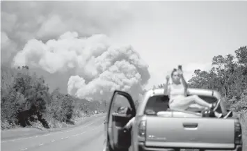  ?? AGENCE FRANCE PRESSE ?? A woman takes a photo as an ash plume rises from the Kilauea volcano on Hawaii’s Big Island.