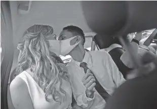  ?? Ap ?? Wearing masks to prevent the spread of the new coronaviru­s, Thiago do nascimento, right, and Keilla de almeida kiss during their drive-thru wedding at the registry office in the neighborho­od of Santa Cruz, rio de Janeiro, Brazil, Thursday, May 28, 2020. Couples have begun turning to this unconventi­onal union at a notary in Santa Cruz since the Covid-19 started battering Brazil.