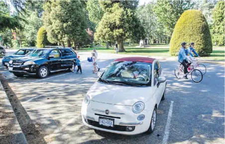  ?? DARREN STONE, TIMES COLONIST ?? Cyclists pass cars in a parking lot on Circle Drive in Beacon Hill Park. Motorists take note: The fine for opening a car unsafely rises to $368 on Sept. 21.
