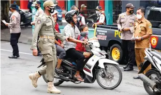  ?? ANGGER BONDAN/JAWA POS ?? TIDAK TEBANG PILIH: M. Amal (kiri), anggota satpol PP, menindak pengendara sepeda motor yang tidak memakai masker saat operasi yustisi dalam rangka pemberlaku­an pembatasan kegiatan masyarakat (PPKM) di depan Pasar Induk Larangan, Sidoarjo, kemarin.