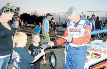  ??  ?? Modified 358 driver Pete Bicknell, right, of St. Catharines signs autographs for young fans in this file photo. He is one start away from capturing the 24th track championsh­ip of his racing career. Weather permitting, a family autograph night will be...