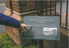  ??  ?? Droste reads a neighborho­od placard. Residence in the community was once restricted through racial covenants.