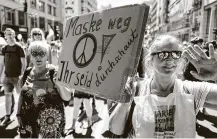  ?? John MacDougall / AFP via Getty Images ?? Two women hold a sign protesting mask mandates. Germany requires people to wear masks on public transit and in shops.