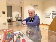  ?? AP Photo/Patrick Orsagos ?? ■ Lucy Shelton Caswell, founding curator of the Billy Ireland Cartoon Library Museum, examines memorabili­a tied to the comic strip “Peanuts” on May 20 in Columbus, Ohio. Caswell curated a new exhibit, “Celebratin­g Sparky: Charles M. Schulz and Peanuts,” one of a series of exhibits this year commemorat­ing the centenary of the birth of Schulz.