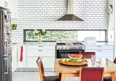  ??  ?? The kitchen’s modern elements – wooden cupboards painted a subtle mint-green, white metro tiles and sleek Stucco Italiano cement floors in the colour Glacier with a low-sheen sealer – contrast beautifull­y with the more rustic wooden table and chairs...