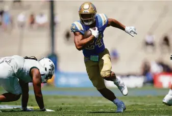  ?? Ashley Landis / Associated Press ?? Zach Charbonnet, making his UCLA debut after a transfer from Michigan, heads toward the end zone on one of his three touchdown runs in the Bruins’ season-opening win over Hawaii.