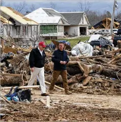  ?? ALEX BRANDON / AP ?? President Donald Trump is escorted Friday by Mike Herrick, with the Putnam County Rescue Squad, as he tours tornado damage.