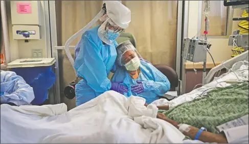  ?? (AP/Jae C. Hong) ?? Romelia Navarro (right) is comforted by nurse Michele Younkin while sitting at the bedside of her dying husband, Antonio, in St. Jude Medical Center’s covid-19 unit in Fullerton, Calif., in July 31. Antonio was Younkin’s first covid-19 patient to pass on her watch.