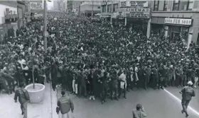  ?? DONALD EMMERICH / MILWAUKEE SENTINEL ?? NAACP Youth Council Commandos link arms at the front of thousands of marchers honoring the Rev. Martin Luther King Jr. as they filled Wisconsin Ave. on April 8, 1968. The peaceful march four days after King’s assassinat­ion was considered the largest...