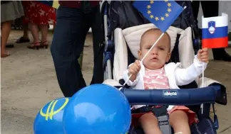  ?? ?? A baby girl waves the European flag along with the Slovenian one while attending a celebratio­n in Brussels, July 11, 2006.