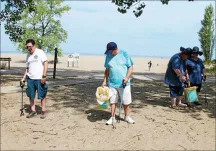  ?? KRISTI GARABRANDT — THE NEWS-HERALD ?? Ed Probst, left, and Tony Cervella participat­e in Lake County Board of DD/Deepwood Recreation Service Program’s beach clean up project at Headlands Beach. Sisters Cody and Kayla also take part.