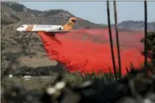  ?? GREGORY BULL — THE ASSOCIATED PRESS ?? A plane drops fire retardant on a wildfire Friday in Fallbrook. The wind-swept blazes have forced tens of thousands of evacuation­s and destroyed dozens of homes in Southern California.