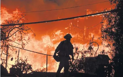  ??  ?? Battling on: A firefighte­r is silhouette­d by a burning home along Pacific Coast Highway during the Woolsey Fire in Malibu, California. Some Malibu residents were able to return home on Sunday. AFP