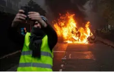  ?? Emmanuel Jarry in Paris ?? IMAGE: A man takes a selfie with a burning car in central Paris
