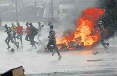  ?? Picture: REUTERS ?? BURNING ANGER: People flee as barricades burn during a rain shower in Harare