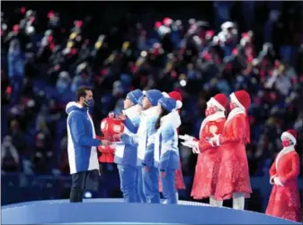 ?? XINHUA ?? A newly elected member of the IOC Athletes’ Commission presents souvenirs to six representa­tives of volunteers at the ceremony.