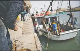  ??  ?? A man, wearing a protective mask, helps docking a fishing boat as it entered Fiumicino fishing port.