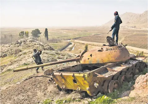  ??  ?? Armed officers take photos of a Soviet tank at a police outpost in Ghargai