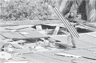  ?? — Gambar Bernama ?? MUSNAH: Seorang pekerja kontrak mengalih serpihan bumbung yang pecah di sebuah kediaman Rumah Rakyat Sikamat ekoran dilanda ribut pada 2.30 petang semalam ketika tinjauan Bernama di Sikamat, semalam.
