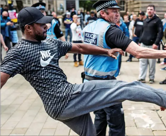  ??  ?? STICKING THE BOOT IN: A Black Lives Matter supporter aims a kick at a rival during a tense stand-off in Bolton, as a police officer at the scene seeks to stop the trouble escalating any further