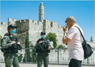  ?? (Olivier Fitoussi/Flash90) ?? BORDER POLICE officers order a Jerusalemi­te to wear a protective mask outside the Jaffa Gate yesterday.