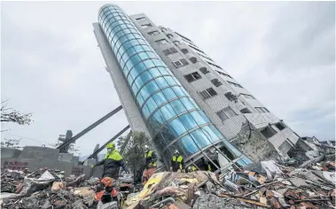  ?? AFP ?? Rescue workers, bottom left, walk out from the Yun Tsui building, which is leaning at a precarious angle in the city of Hualien.