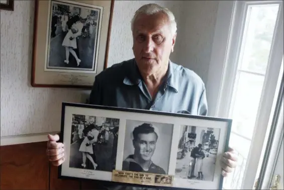  ?? CONNIE GROSCH — PROVIDENCE JOURNAL VIA AP ?? George Mendonsa poses for a photo in Middletown, R.I., holding a copy of the famous Alfred Eisenstadt photo of Mendonsa kissing a woman in a nurse’s uniform in Times Square on while celebratin­g the end of World War II, left. Mendonsa died Sunday he was 95. It was years after the photo was taken that Mendonsa and Greta Zimmer Friedman, a dental assistant in a nurse’s uniform, were confirmed to be the couple.