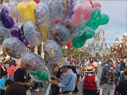  ?? GABRIELLE RUSSON/ORLANDO SENTINEL/TNS ?? A Disney World employee sells balloons at the crowded Magic Kingdom park after Christmas.