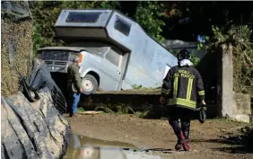  ??  ?? Damage: A fireman walks towards a motorhome in a ditch near the house where two families drowned in Casteldacc­ia, near Palermo