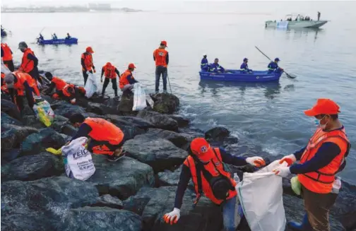  ?? Reuters ?? ↑
Government workers and volunteers pick up trash along the Manila Bay shore during the Internatio­nal Coastal Cleanup Day in Manila on Saturday.