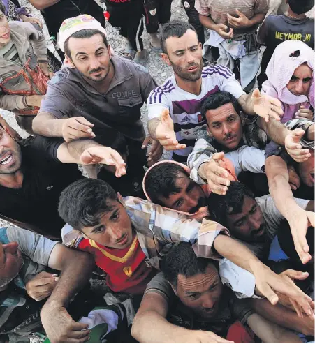  ??  ?? Members of the Yazidi community gather for humanitari­an aid on the Syria-Iraq border at Feeshkhabo­ur, in northern Iraq.