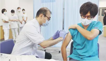  ?? — AFP photo ?? A man (right) receives a third dose of the Pfizer vaccine against the Covid-19 coronaviru­s at the Tokyo Medical Centre in Tokyo.