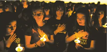  ??  ?? People attend a candleligh­t vigil for victims of the shooting at nearby Marjory Stoneman Douglas High School, in Parkland, Florida, on Thursday