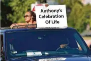  ??  ?? A family member holds a sign during a procession of vehicles driving past the photos in the park.