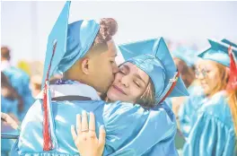  ??  ?? LEFT: Alexis Rodriguez Hernandez kisses Adriana Mendoza Ortiz on Friday following Capital High School’s commenceme­nt ceremony.