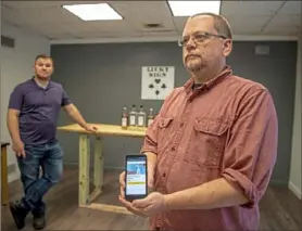  ?? Alexandra Wimley/Post-Gazette ?? Christian Kahle, right, of Lucky Sign Spirits, displays a GoFundMe page, with Matthew Brudnok, left, in the distillery in Spring Garden. They started a fundraiser through GoFundMe to be able to make hand sanitizer to donate to first responders.