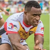  ??  ?? Kumul action ... a PNG player on the burst during a match against an Australian Prime Minister's XIII (opposite page); face of determinat­ion; the Kumuls in a huddle.