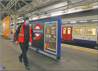  ??  ?? Joseph Cocks, a tube train driver, walks from the front to the back of the train along the platform at Hammersmit­h Undergroun­d station before taking the train round the Circle Line in London.