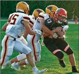  ??  ?? A swarm of New Bremen Cardinals look to take down Coldwater’s Reece Dellinger on Friday.