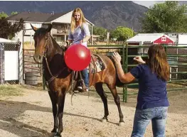  ?? Photo: Ed Helmick ?? Chyrah and her mother demonstrat­e the mustang’s composure. By throwing a plastic ball in its direction.