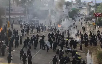  ?? PHOTO/LUIS ALBERTO CRUZ HERNANDEZ ?? Riot police gather and regroup as they battle all day with protesting teachers who were blocking a federal highway in the state of Oaxaca, near the town of Nochixtlan, Mexico, on Sunday. The teachers are protesting against plans to overhaul the...