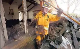  ?? Al Seib Los Angeles Times ?? SAN MIGUEL firefighte­r Jason Taylor searches a damaged home on Olive Mill Road for victims. At least 100 single-family homes were destroyed in the slides.