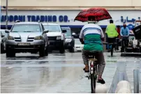  ?? Photo by Neeraj Murali ?? A cyclist enjoys his ride without getting wet as he balances his umbrella during light showers in Dubai. —